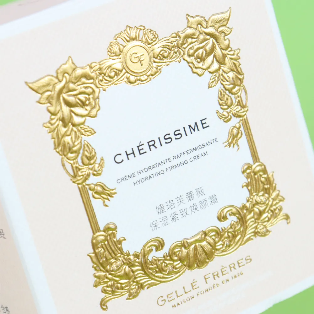 Close-up detail of elegant custom gold embossed vintage floral frame logo on pale beige tuck folding carton lid