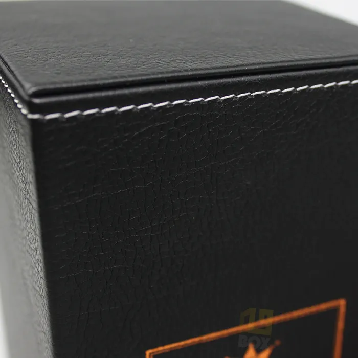 Close up edge detail of neat white simulated stitching wrapping the corners of black faux leather texture candle boxes
