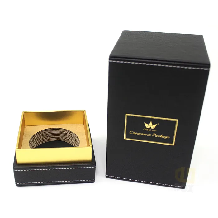Front panel close-up of black faux leather candle boxes featuring warm copper metallic hot foil framed logo print detail
