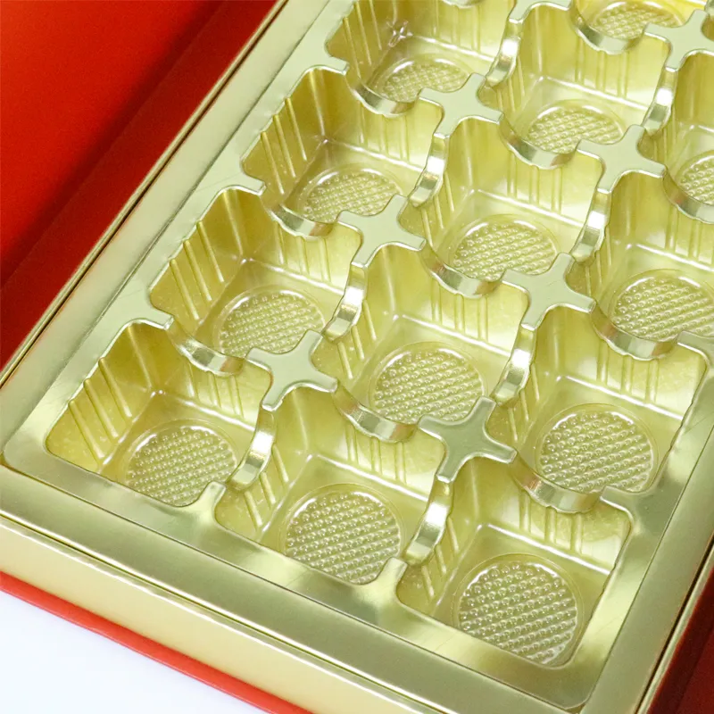 Close-up shot of food-safe golden plastic blister grid cavity insert inside chocolate double door box, separate recesses for truffle bonbons