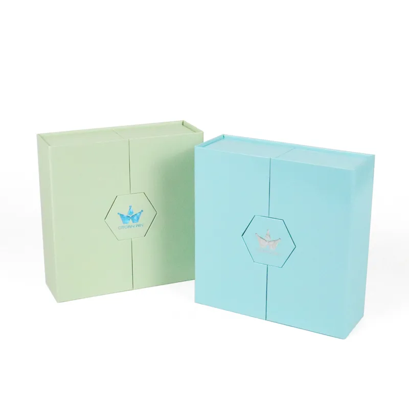 Paired closed pastel mint green and sky blue double door box front view, central hexagon cutout with foil crown logo, foldable cosmetic gift packaging