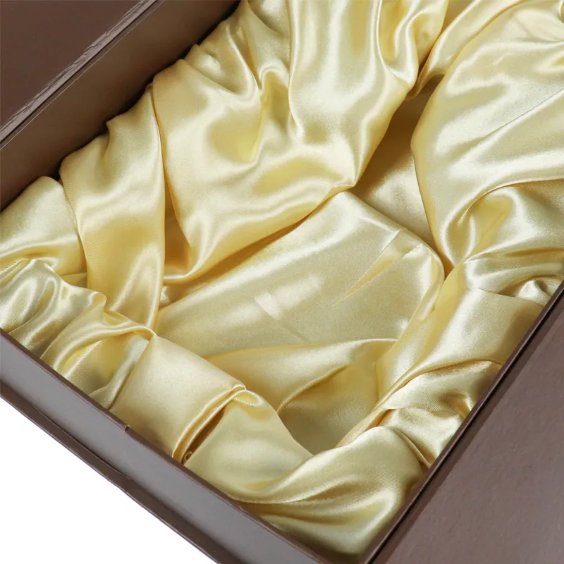 Close-up of soft gathered golden satin fabric lining inside double door wine gift box