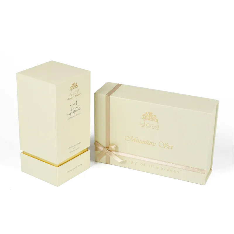 Mini serum and cream bottles placed beside open cream ribbon magnetic skincare packaging box, silk interior custom skincare packaging for cosmetic gift sets