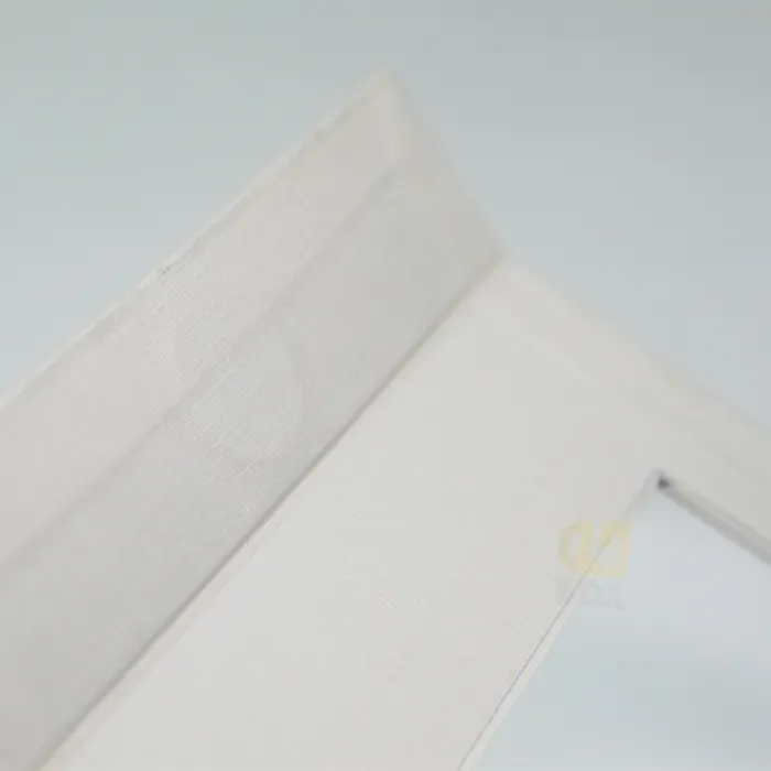 Detail view of textured specialty paper wrapping and neat folded edge on rigid window box packaging