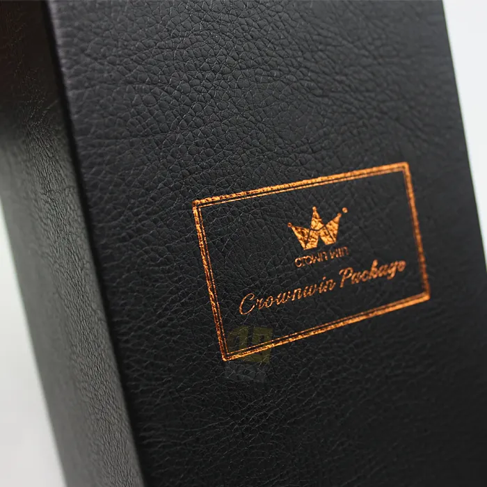 Macro close-up of shiny copper metallic hot foil logo and text printed on matte black faux leather candle box surface
