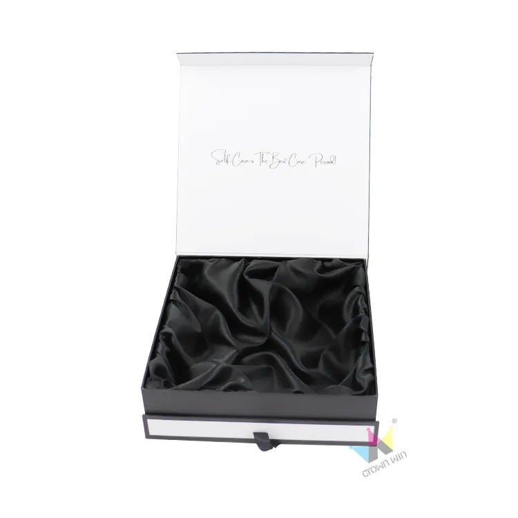 Open black white magnetic box lined with wrinkled black satin fabric, luxury packaging for self-care gift sets