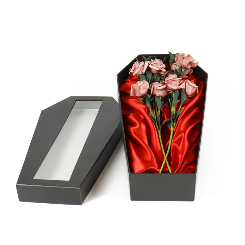 Opened matte black coffin shaped window box packaging with red satin lining and artificial dusty pink roses