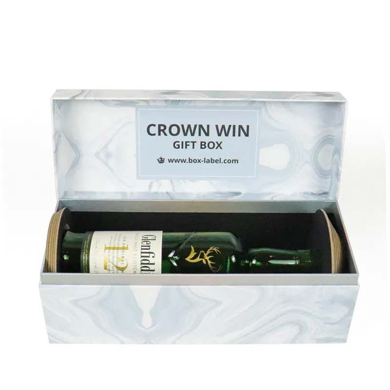 Open grey swirl marble magnetic closure boxes with custom black foam cradle holding single green glass whiskey bottle, rigid liquor gift packaging
