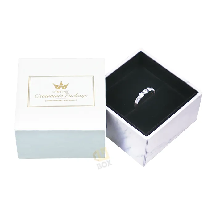 Opened marble print slide out drawer box lined with soft black velvet, holding a diamond ring inside premium jewelry drawer box