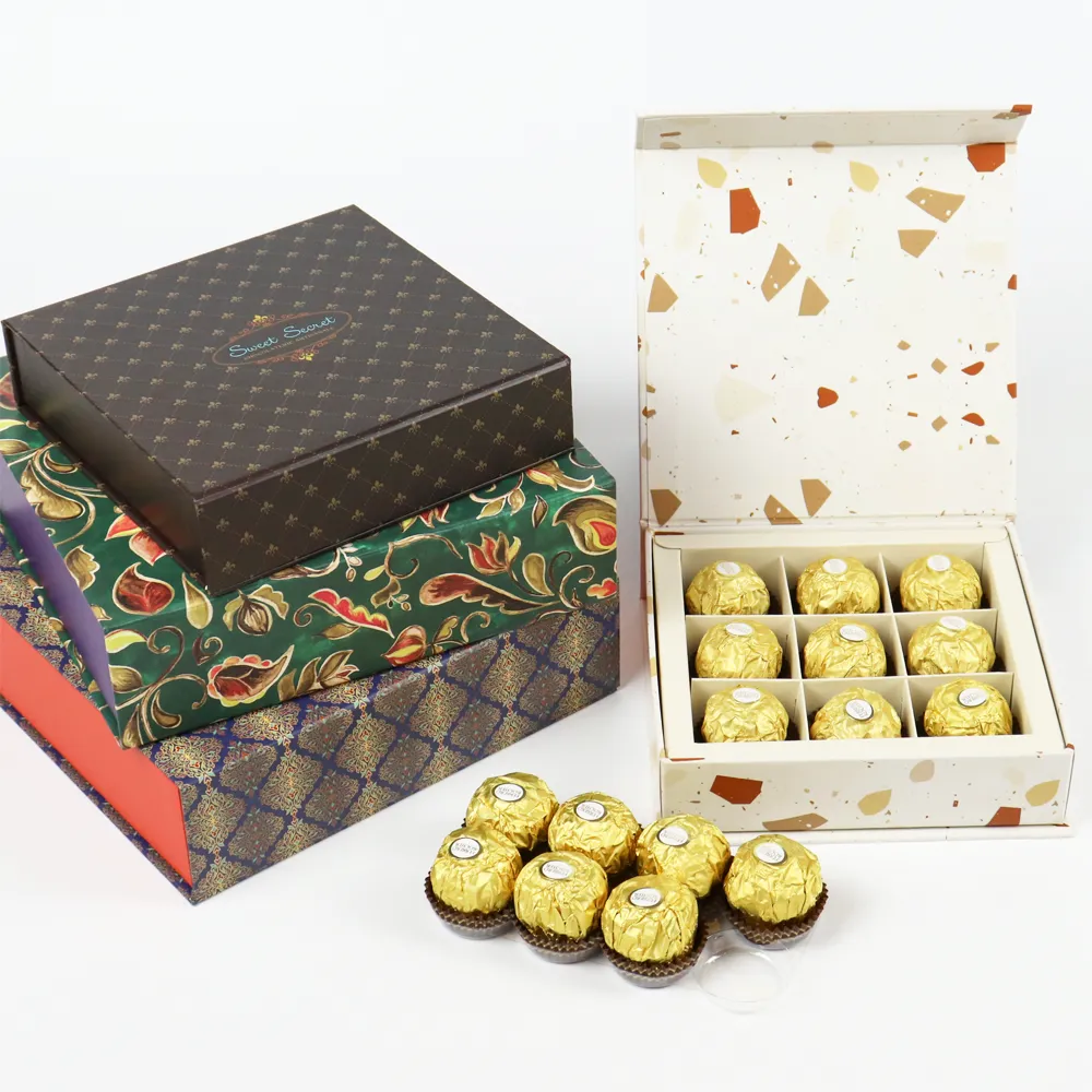 Opened speckled interior magnetic box with divided grid tray, loose gold wrapped chocolate truffles laid outside the magnetic box
