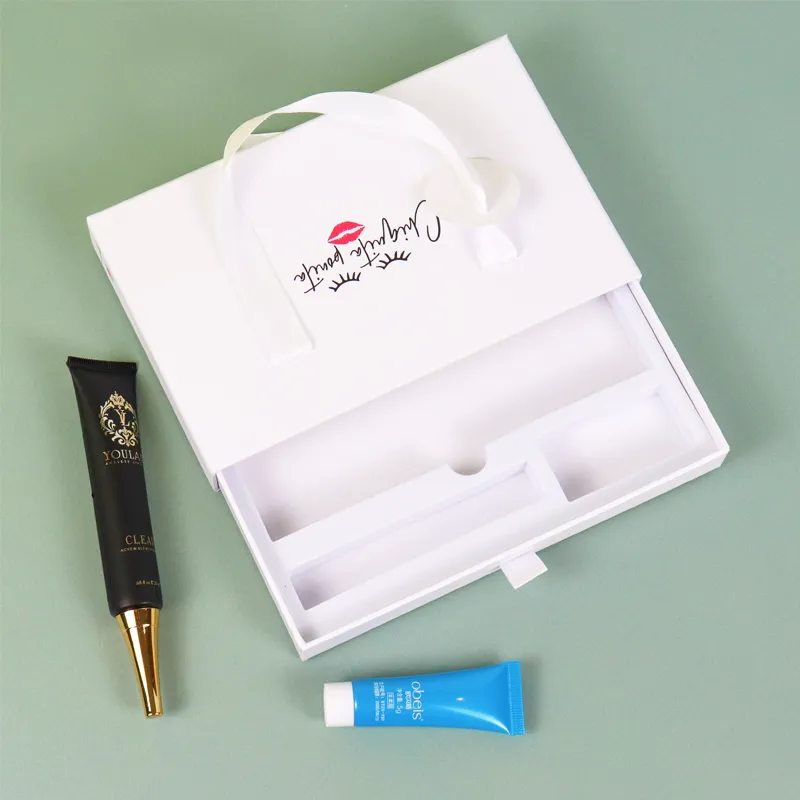 Side angle closed rigid cosmetic boxes close-up of integrated satin ribbon carry handle and round paper hang tag detail