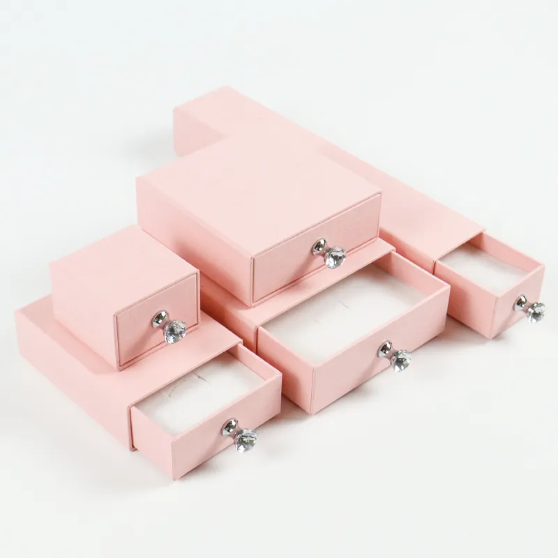 Three-quarter angled overview of all five dimension pink linen jewelry drawer box with matching crystal handle knobs