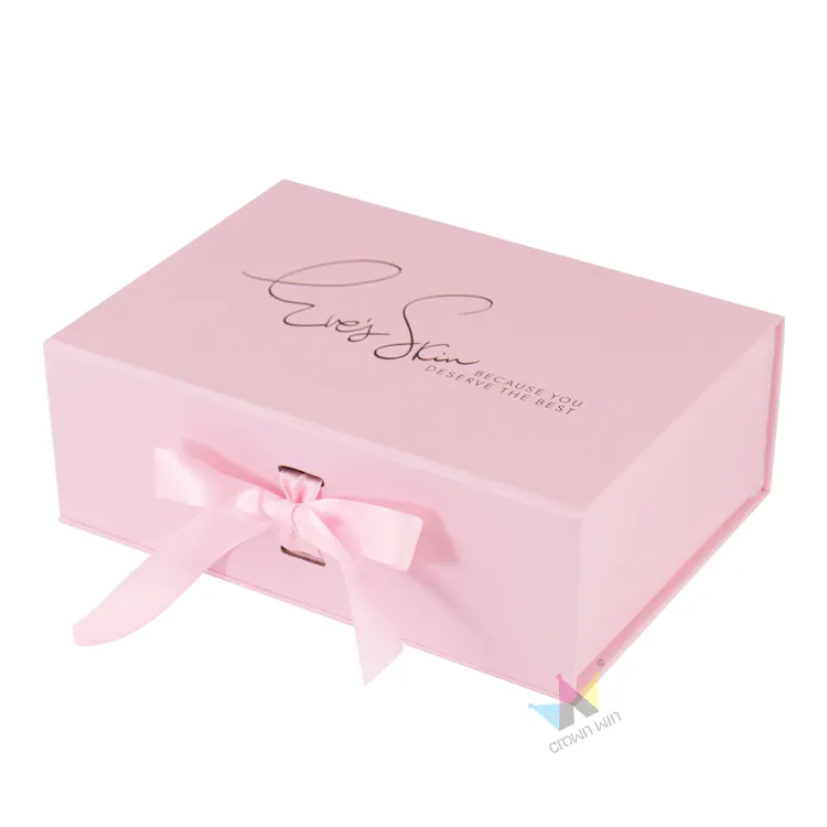 Three-quarter front view of rigid pink magnetic gift box with neat satin ribbon bow closure and printed brand slogan