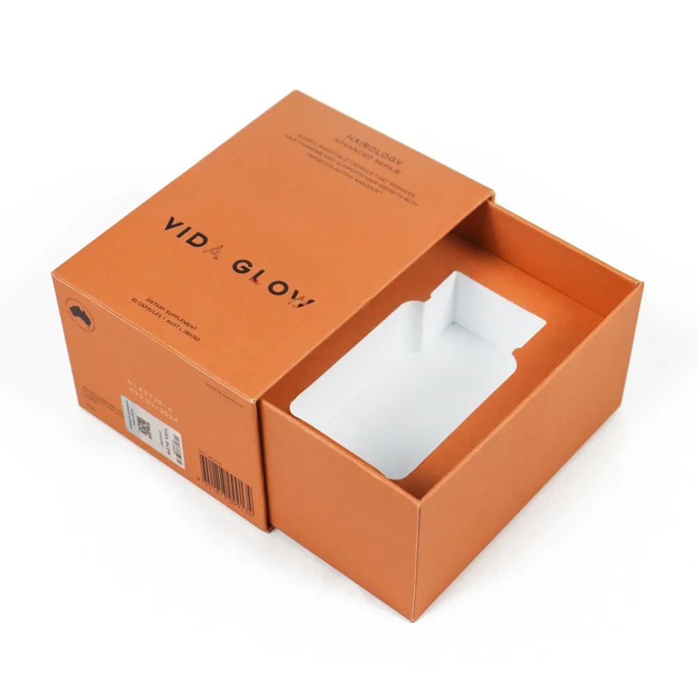 Top down overhead shot of fully slid-out drawer orange perfume boxes showing fitted molded white paper inner support tray