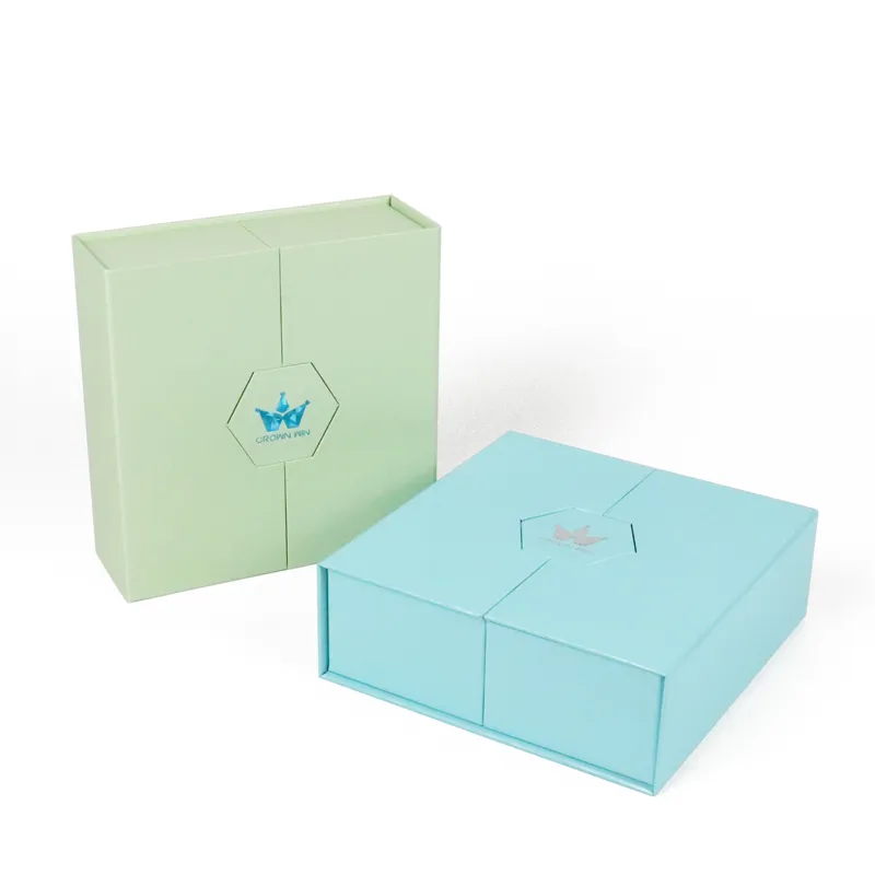 Paired closed pastel mint green and sky blue double door box front view, central hexagon cutout with foil crown logo, foldable cosmetic gift packaging