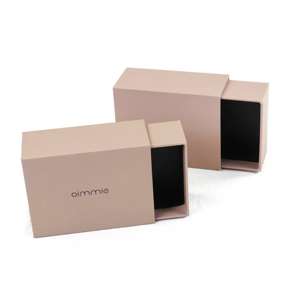 Two sizes of minimalist rigid perfume boxes partially slid open, showing solid black paper interior lining inside nude drawer sleeves