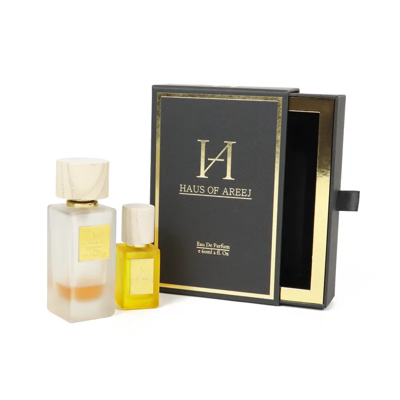 Large and small two fragrance bottles displayed beside fully opened gold interior slide drawer luxury perfume boxes