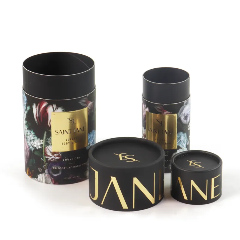 Two sizes of matte black floral gold foil cylinder boxes standing side-by-side, custom rigid paper tube packaging for luxury skincare serum bottles