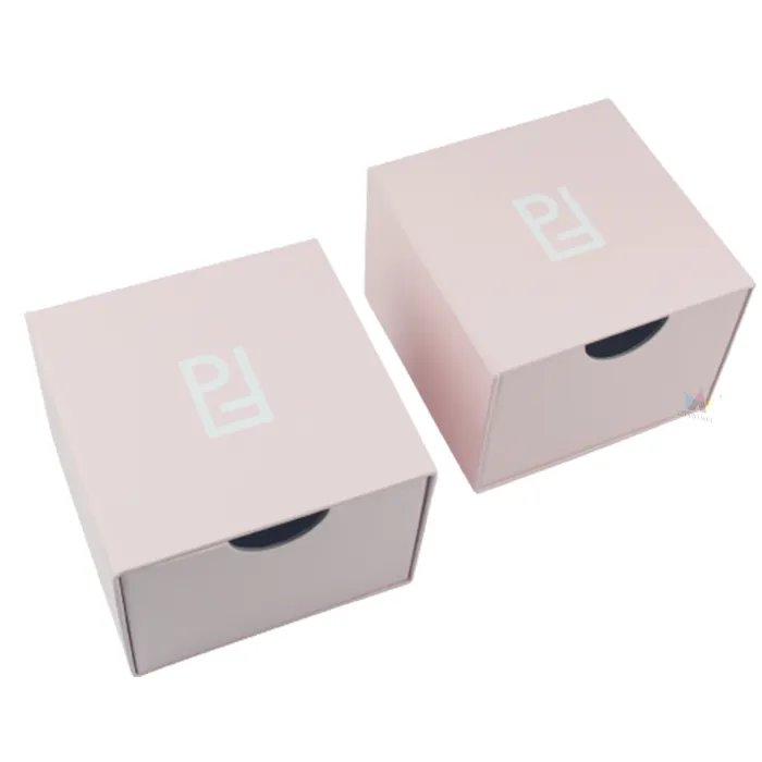 Two stacked closed pastel pink slide drawer essential oil boxes with custom white printed logo on matte lid surface