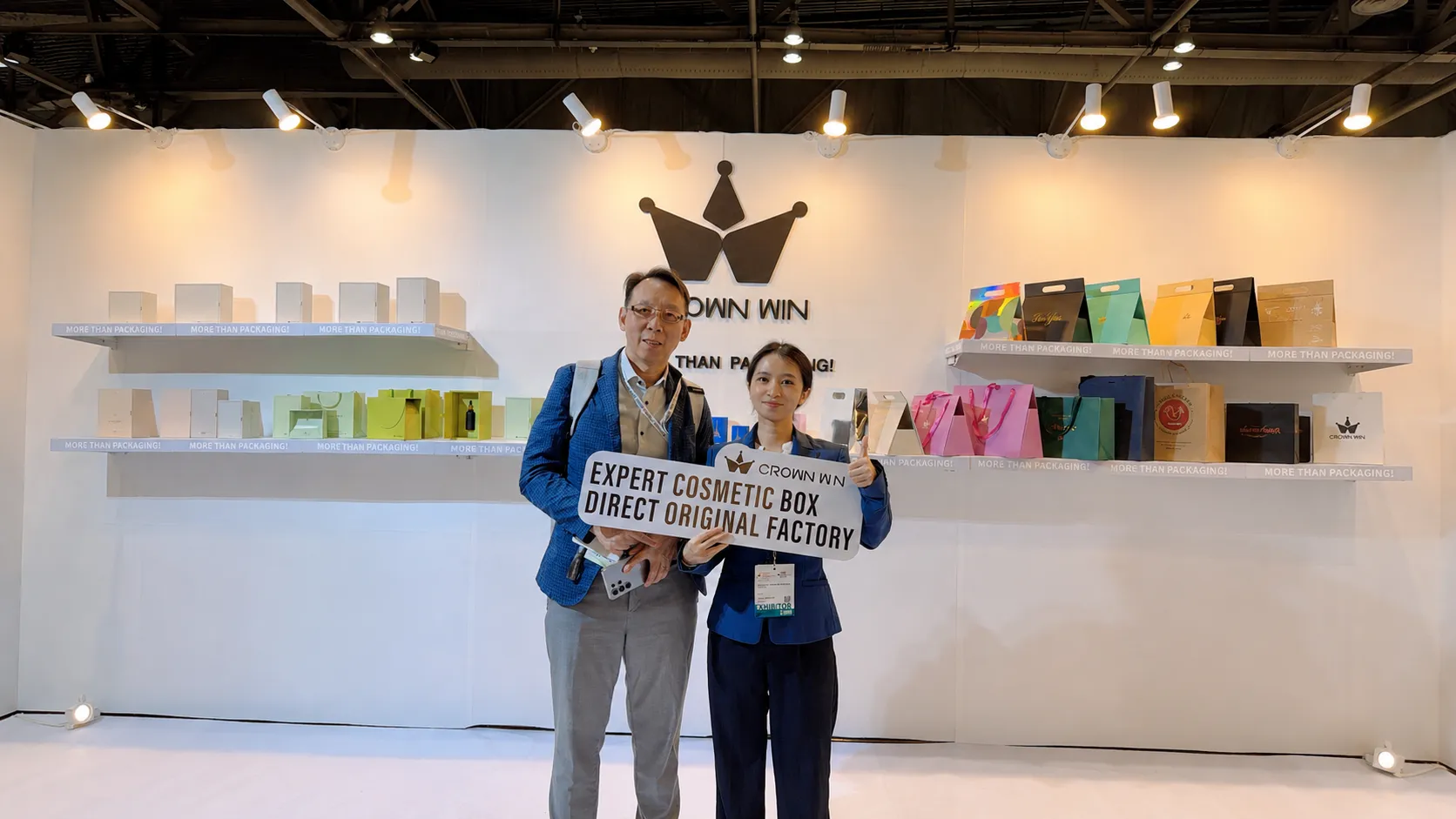 Crown Win team member taking photo with buyer at Hong Kong packaging fair booth, custom cosmetic paper boxes and gift bags display