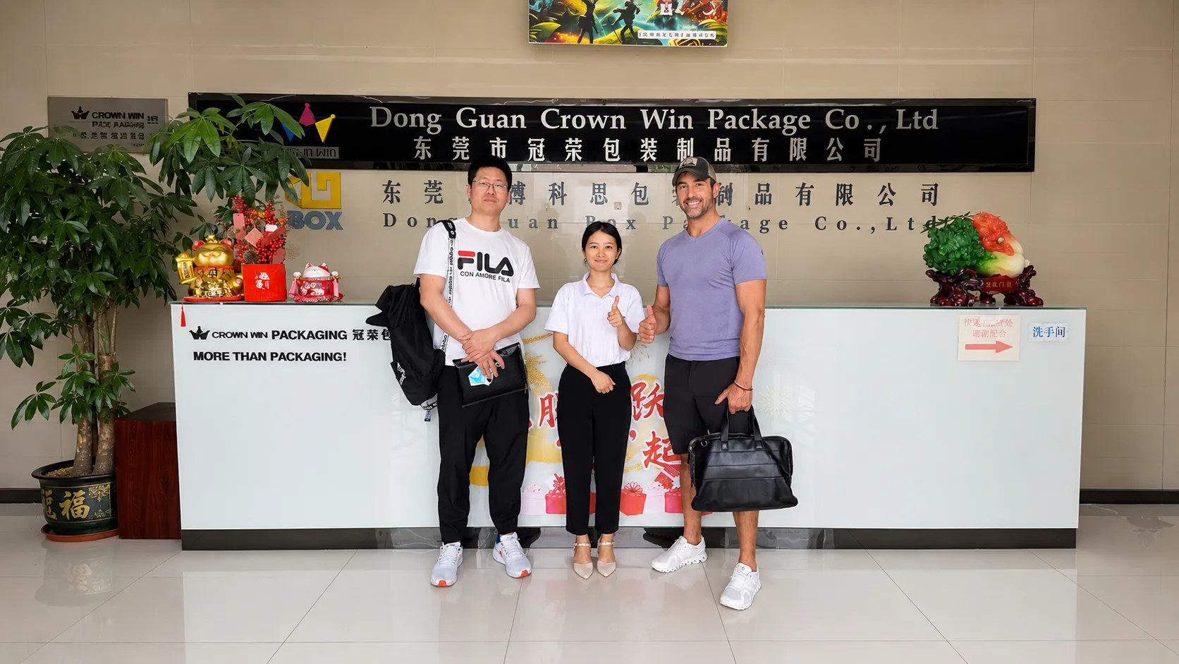 El equipo de Crown Win Packaging da la bienvenida a un cliente norteamericano de la industria de artículos para el hogar en el mostrador de recepción de Dongguan para realizar una auditoría de fábrica y discutir un proyecto de empaques rígidos a medida.