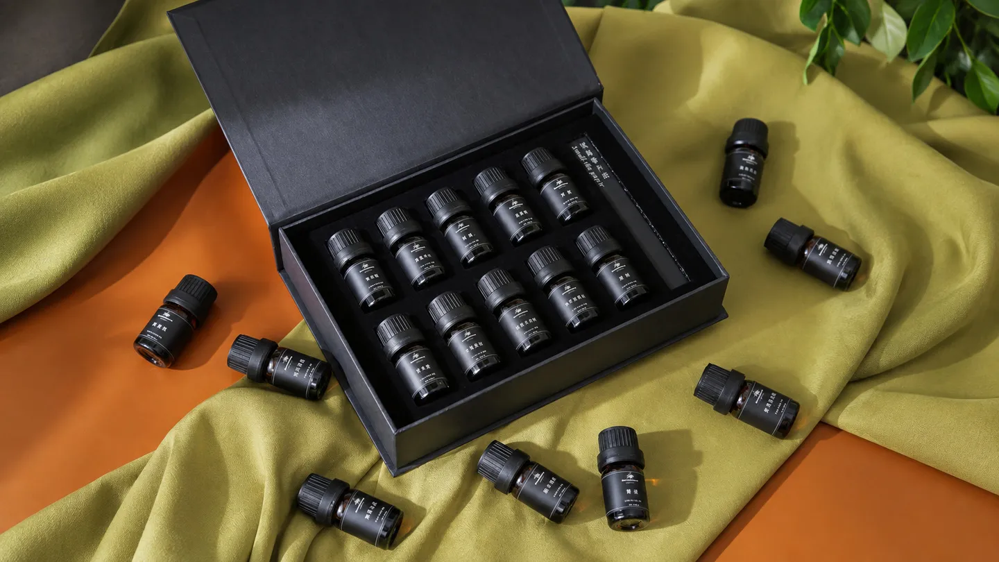Pequeñas botellas de vidrio oscuro dispuestas en un inserto a medida dentro de una caja de presentación negra abierta