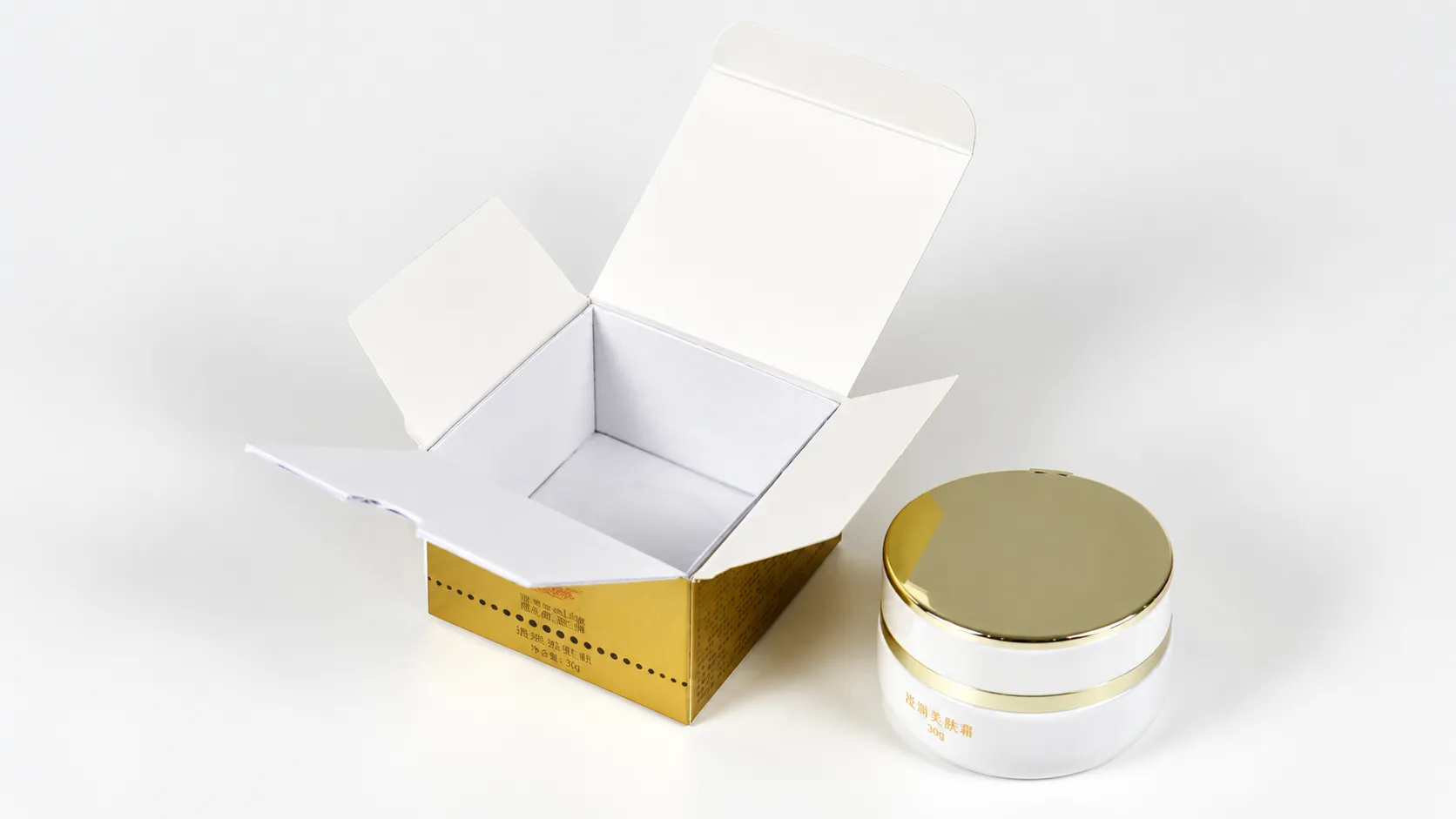 Open gold-printed cosmetic box displayed with a cream jar